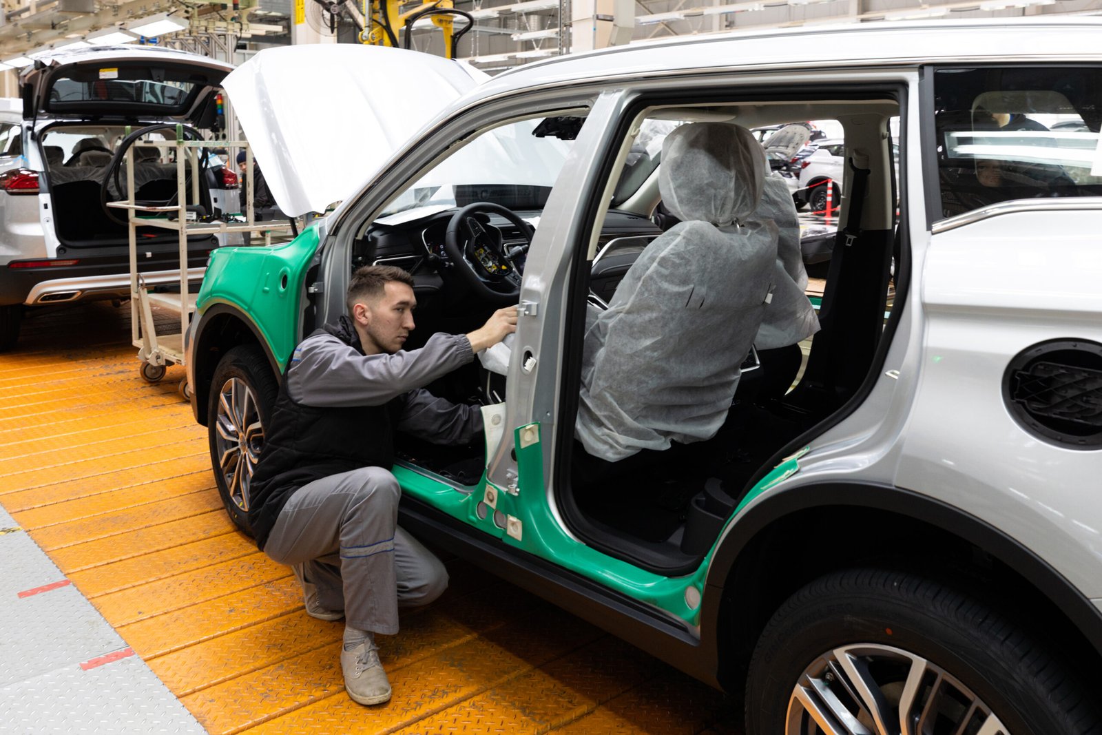 Home minsk, belarus dec 15, 2021: car bodies are on assembly line. factory for production of cars. modern automotive industry. electric car factory, conveyor, workers